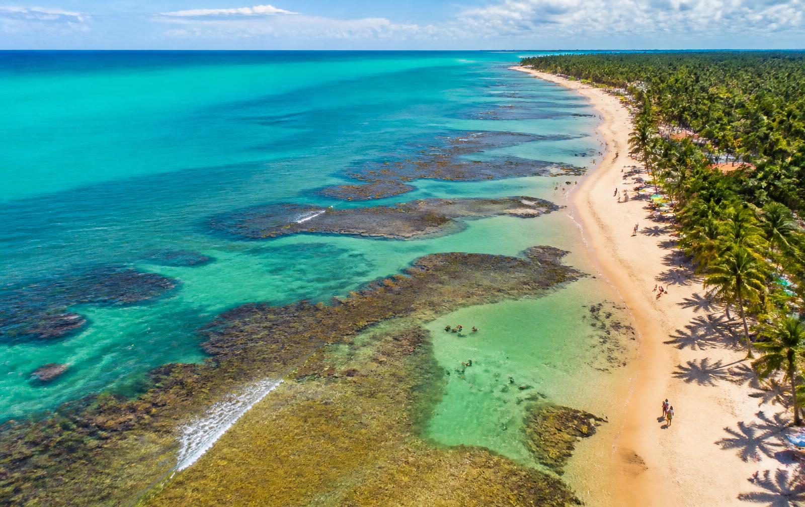 Vista aérea da Praia de Coroa Vermelha com recifes e coqueiros
